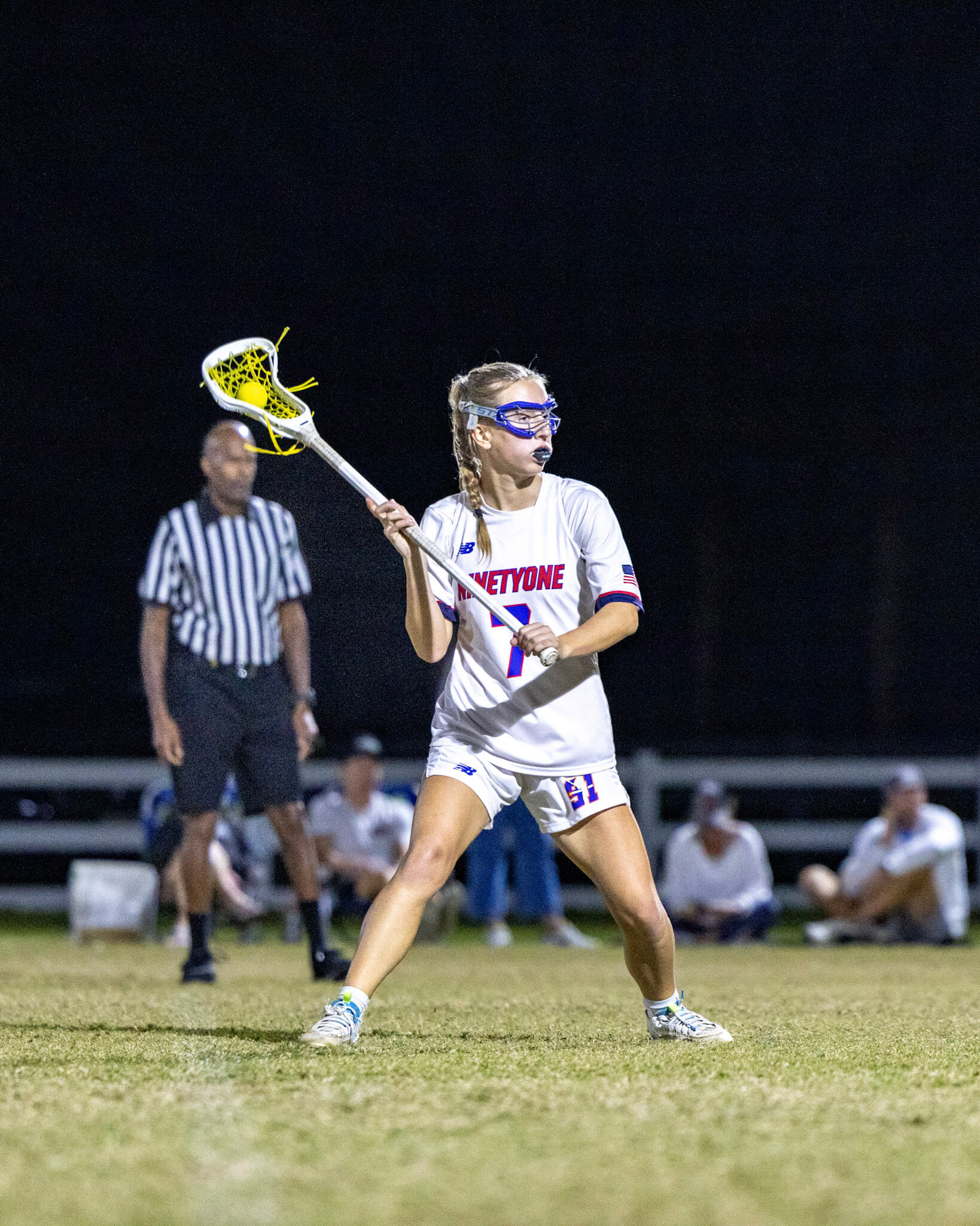 High school girls' lacrosse player at a night game